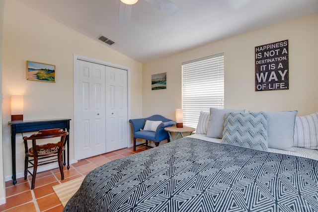 bedroom featuring lofted ceiling, light tile patterned flooring, visible vents, a ceiling fan, and a closet