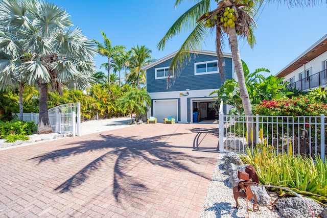 view of front of property featuring decorative driveway, fence, and a gate