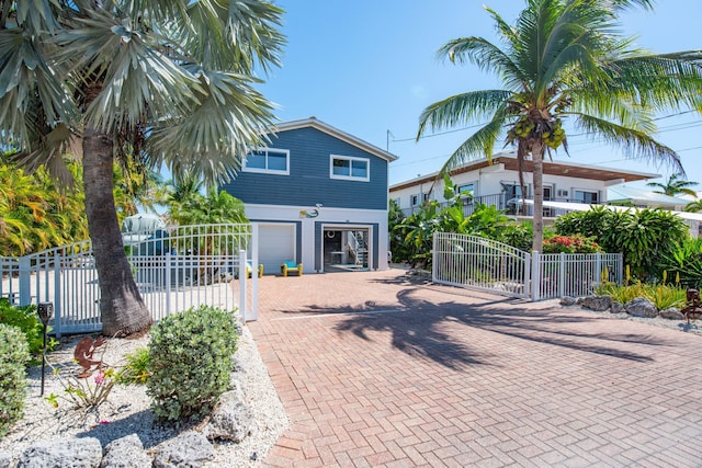 view of front of house featuring a garage, a gate, fence, and decorative driveway