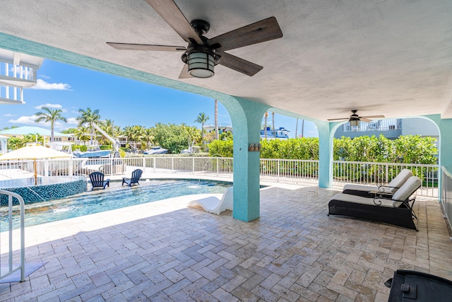 view of swimming pool with pool water feature, ceiling fan, and a patio area