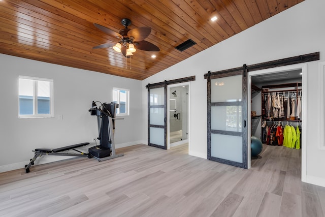 workout area featuring lofted ceiling, wooden ceiling, a barn door, and light wood-type flooring