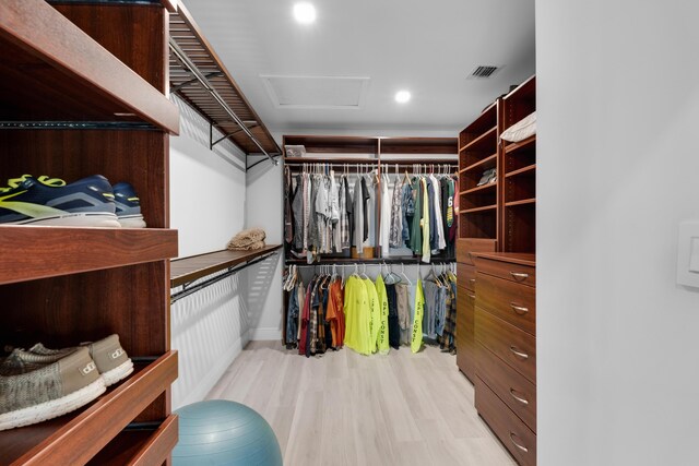 walk in closet with light hardwood / wood-style floors