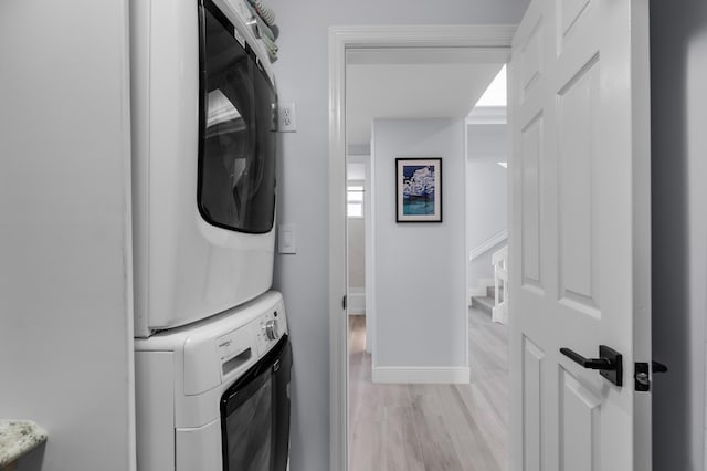 clothes washing area featuring light hardwood / wood-style floors and stacked washing maching and dryer