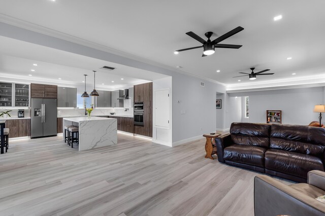 living room featuring ornamental molding, ceiling fan, and light wood-type flooring