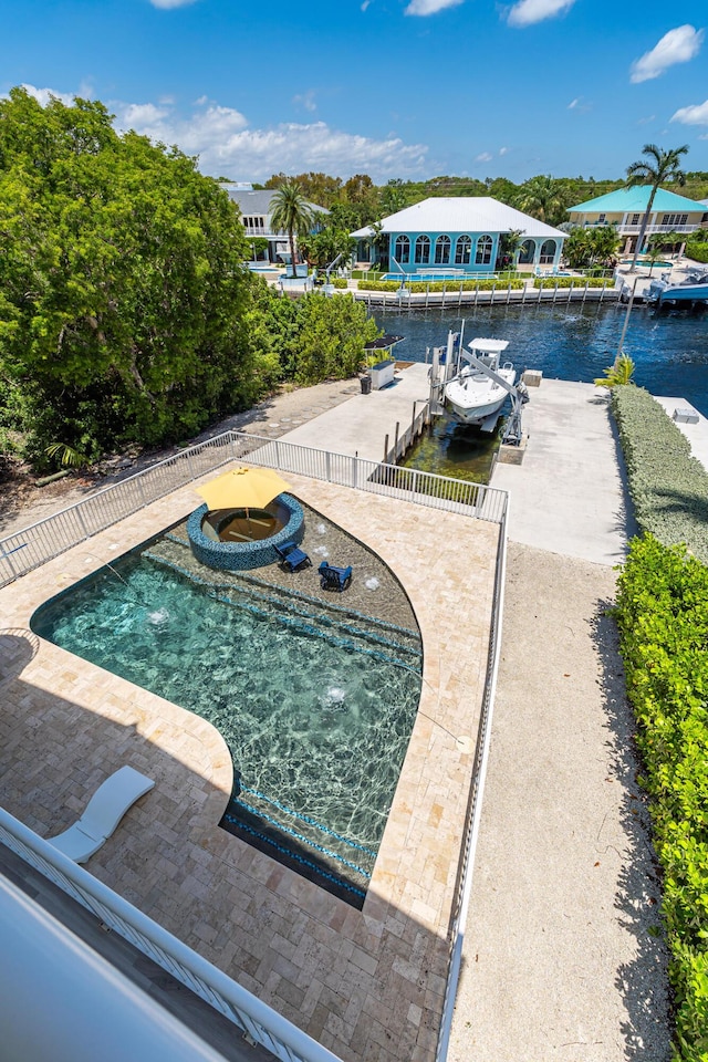 view of swimming pool with a dock, an in ground hot tub, and a water view