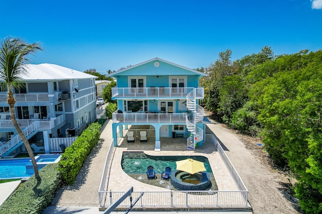 back of property with a pool with hot tub, a patio area, a balcony, and ceiling fan