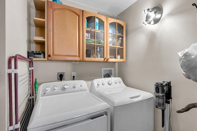 clothes washing area featuring washing machine and dryer and cabinets