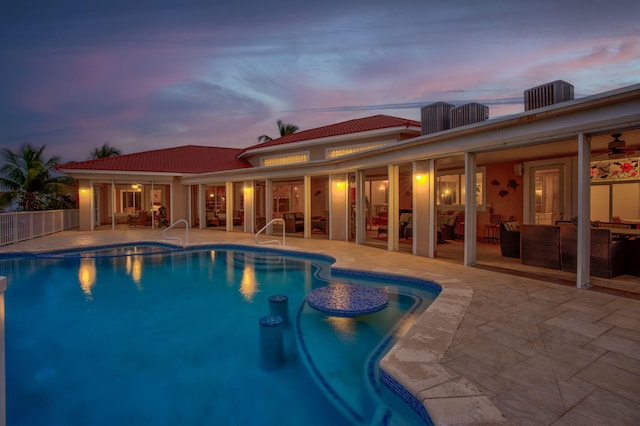 pool at dusk featuring a patio and outdoor lounge area