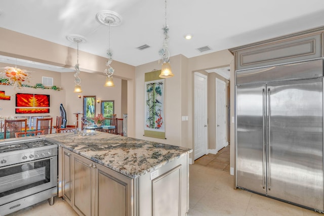 kitchen with hanging light fixtures, light tile patterned floors, kitchen peninsula, stainless steel appliances, and light stone countertops