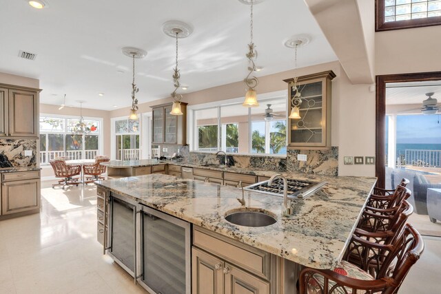 kitchen with a breakfast bar area, wine cooler, tasteful backsplash, light stone countertops, and decorative light fixtures