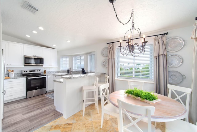 22988 Port Royal Ln, Cudjoe, FL 33042 - kitchen with appliances with stainless steel finishes, a chandelier, white cabinetry, a peninsula, and light stone countertops
