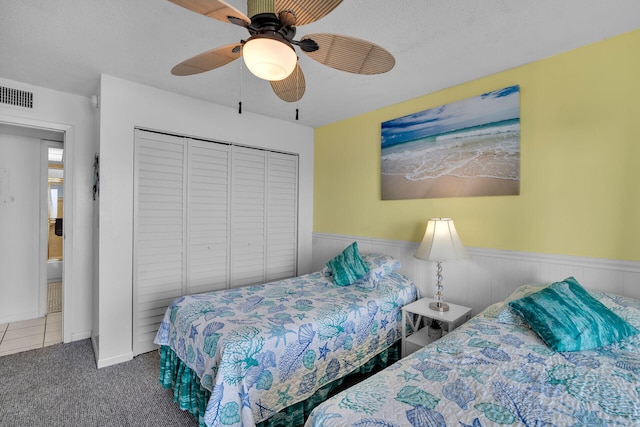 carpeted bedroom with ceiling fan, a closet, and a textured ceiling