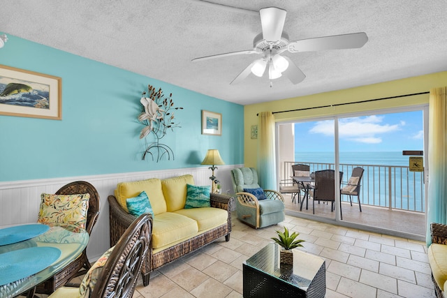 living room with ceiling fan, a textured ceiling, and a water view