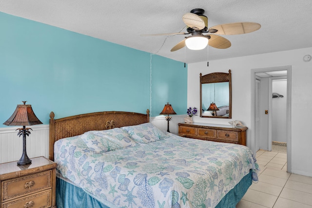 tiled bedroom featuring ceiling fan and a textured ceiling