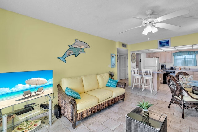 living room featuring sink, a textured ceiling, and ceiling fan