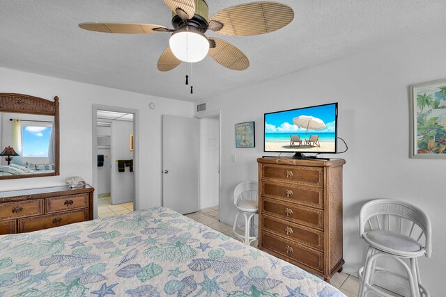 tiled bedroom with ceiling fan and a textured ceiling