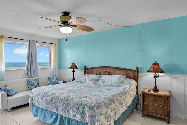 bedroom featuring ceiling fan, light tile patterned floors, a textured ceiling, and a water view