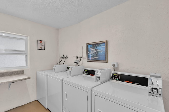 laundry area with independent washer and dryer and a textured ceiling