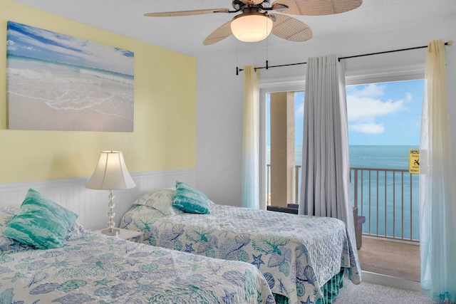 carpeted bedroom with a water view and ceiling fan