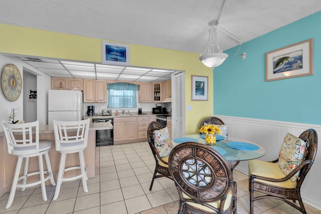 dining area with a drop ceiling, sink, a textured ceiling, and light tile patterned floors