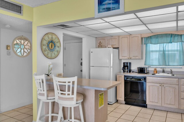 kitchen featuring sink, a breakfast bar, dishwasher, white refrigerator, and light brown cabinetry