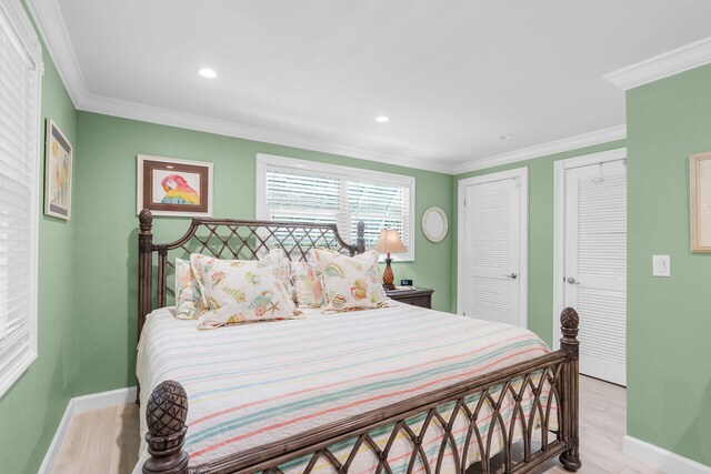 bedroom featuring multiple closets, ornamental molding, and light hardwood / wood-style floors