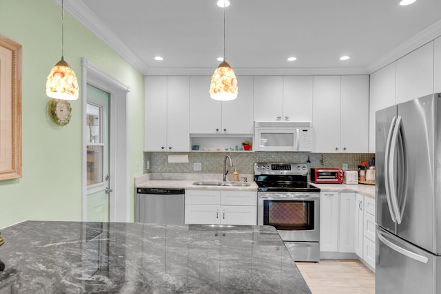 kitchen with stainless steel appliances, white cabinetry, hanging light fixtures, and sink