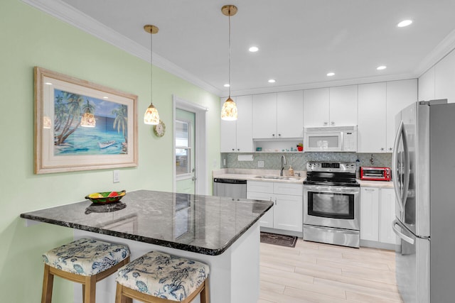 kitchen featuring pendant lighting, sink, appliances with stainless steel finishes, white cabinetry, and a kitchen breakfast bar