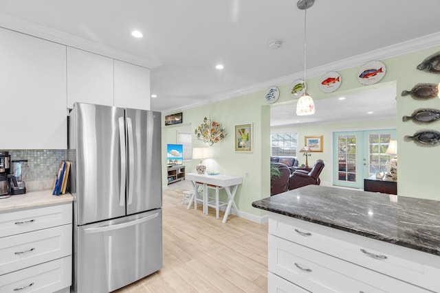 kitchen featuring pendant lighting, stainless steel fridge, crown molding, and white cabinets