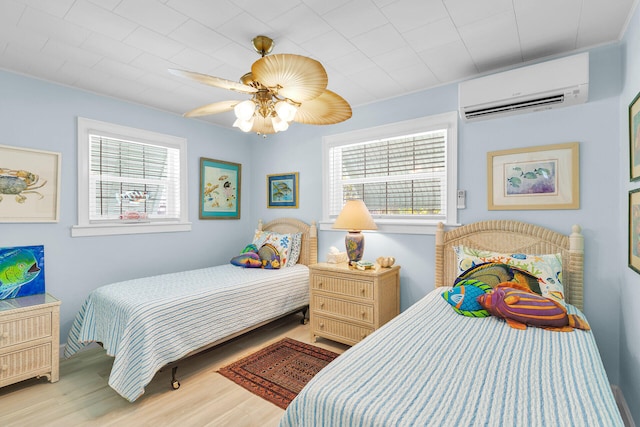 bedroom featuring ceiling fan, a wall mounted air conditioner, multiple windows, and light wood-type flooring