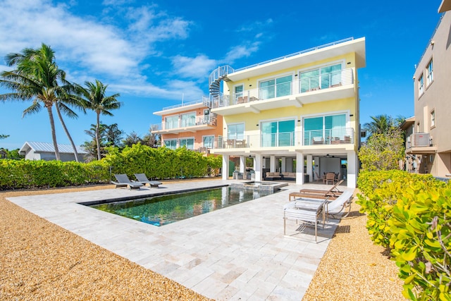 rear view of property featuring a fenced in pool, a patio, and a balcony