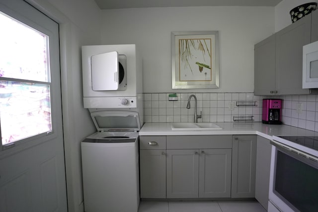 washroom with sink, a wealth of natural light, and stacked washer and clothes dryer