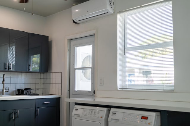 kitchen with washer and dryer, sink, a wall unit AC, and backsplash