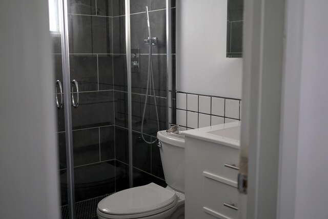 bathroom featuring tile walls, decorative backsplash, vanity, an enclosed shower, and toilet