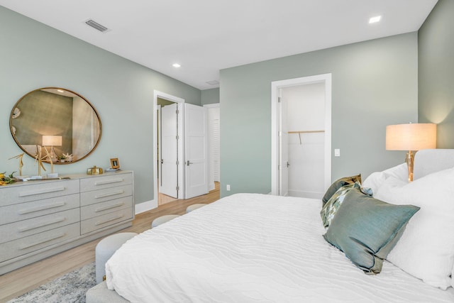 bedroom with a walk in closet and light hardwood / wood-style flooring