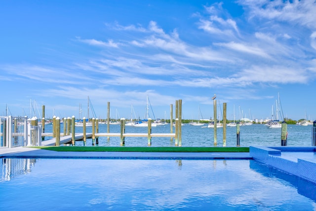 view of swimming pool with a water view and a dock