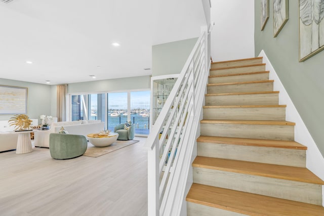 staircase with a water view and hardwood / wood-style flooring