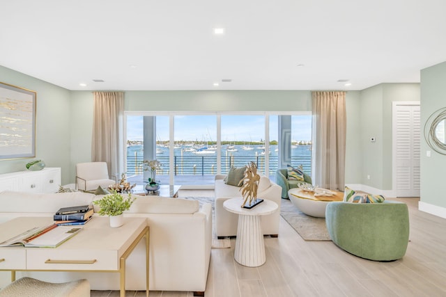 living room featuring a water view, a healthy amount of sunlight, and light hardwood / wood-style flooring