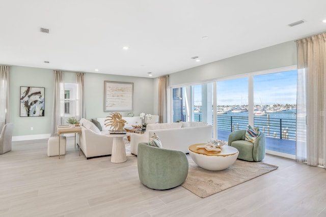 living room with a water view and light hardwood / wood-style floors