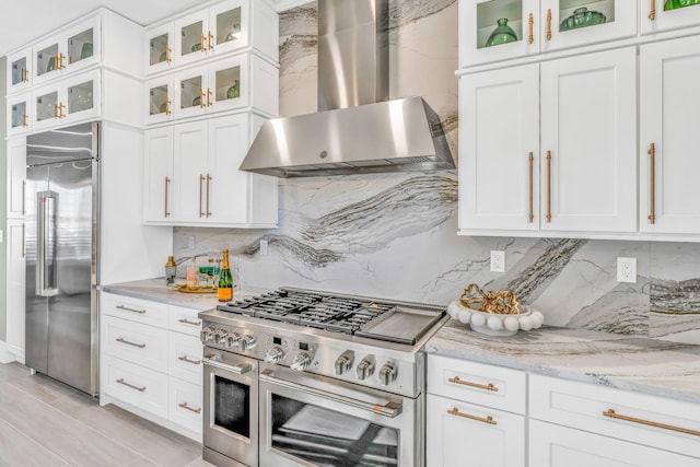 kitchen featuring white cabinetry, wall chimney range hood, and premium appliances