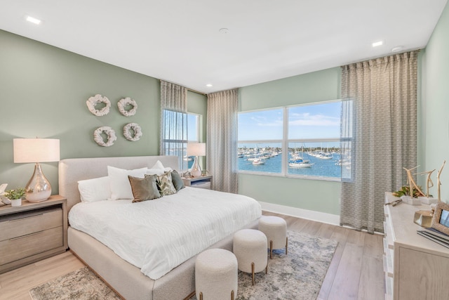 bedroom featuring a water view and light wood-type flooring