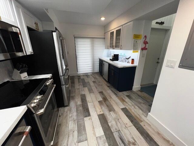 kitchen featuring white cabinetry, light hardwood / wood-style flooring, stainless steel appliances, and blue cabinetry