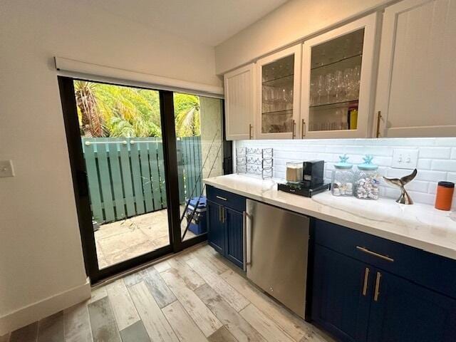 kitchen featuring tasteful backsplash, light hardwood / wood-style flooring, blue cabinetry, and white cabinets