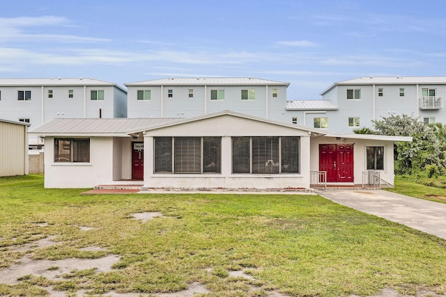 rear view of property with metal roof, a lawn, and stucco siding