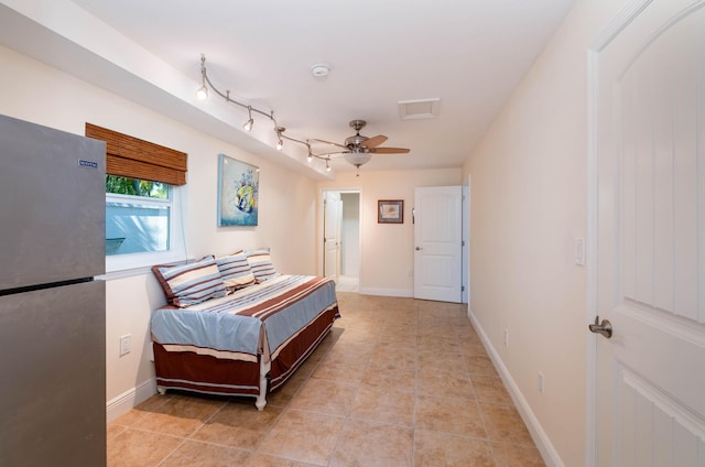 bedroom featuring light tile patterned flooring and stainless steel refrigerator