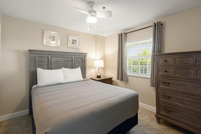 bedroom featuring ceiling fan, a textured ceiling, and light tile patterned floors