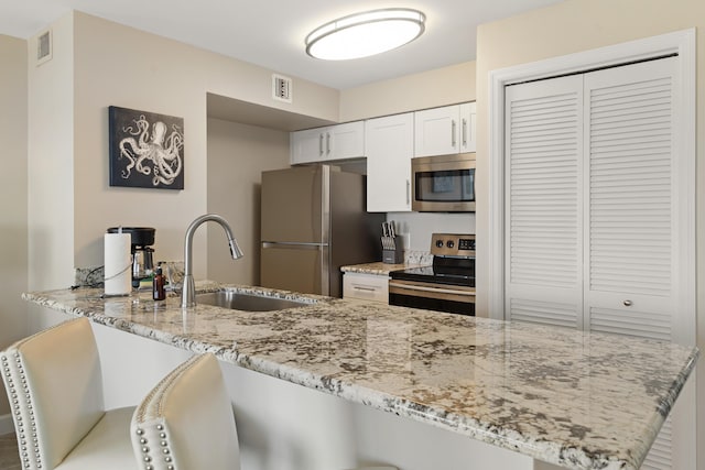 kitchen featuring white cabinetry, sink, light stone counters, kitchen peninsula, and stainless steel appliances