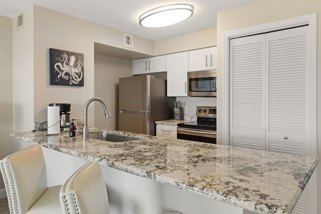 500 Burton Dr Unit 3406, Tavernier, FL 33070 - kitchen featuring stainless steel appliances, a sink, light stone counters, a peninsula, and white cabinetry