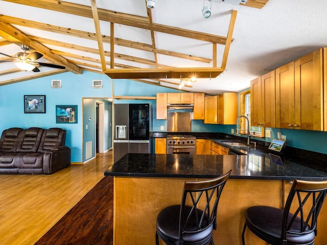 kitchen with a breakfast bar, high end stainless steel range, sink, dark hardwood / wood-style floors, and kitchen peninsula