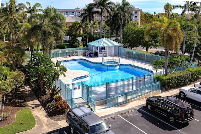 view of swimming pool with a pool with connected hot tub, a patio area, and fence